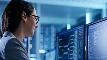 woman working in front of two computer screens