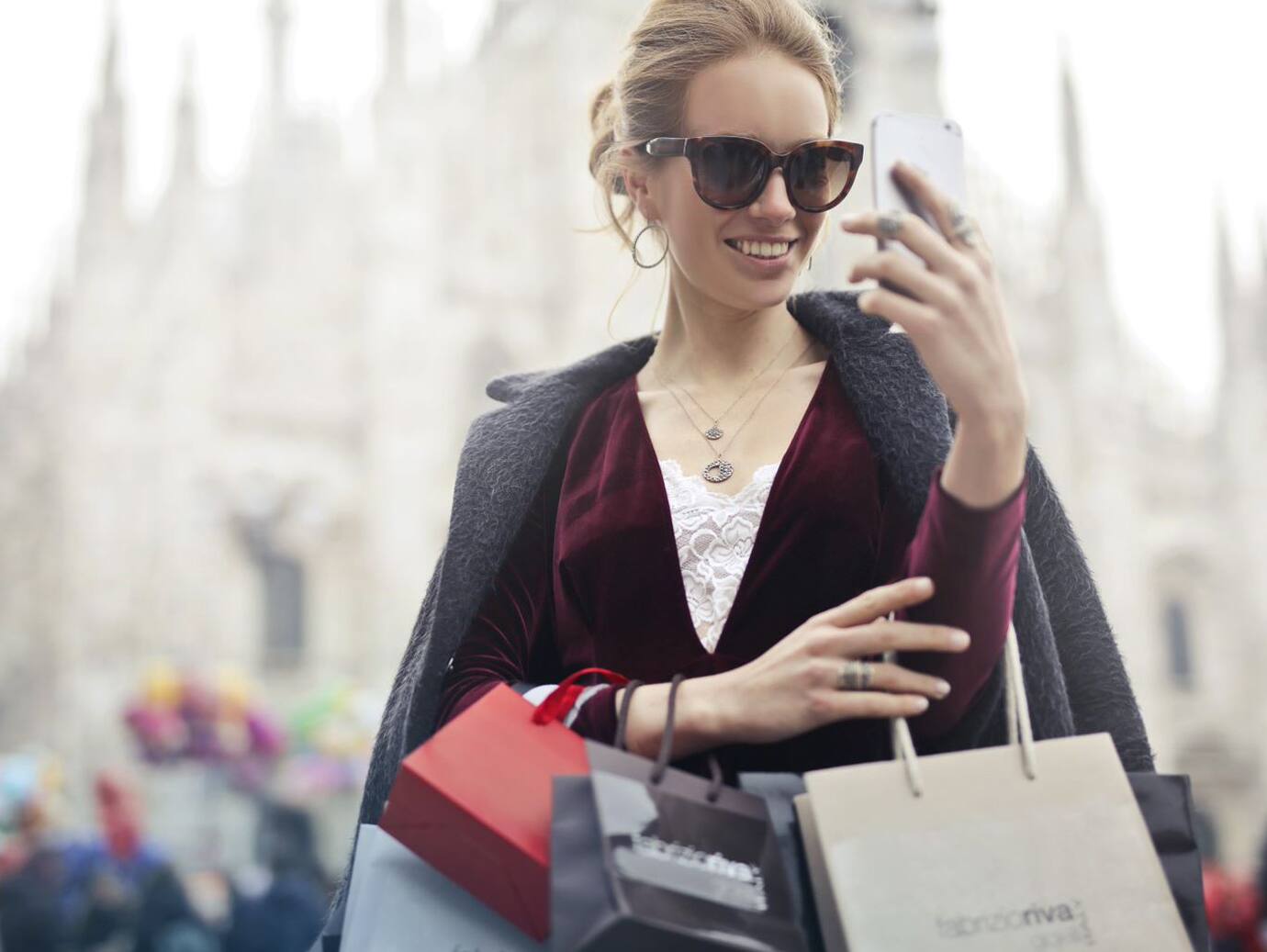 woman carrying shopping bags and looking at her phone
